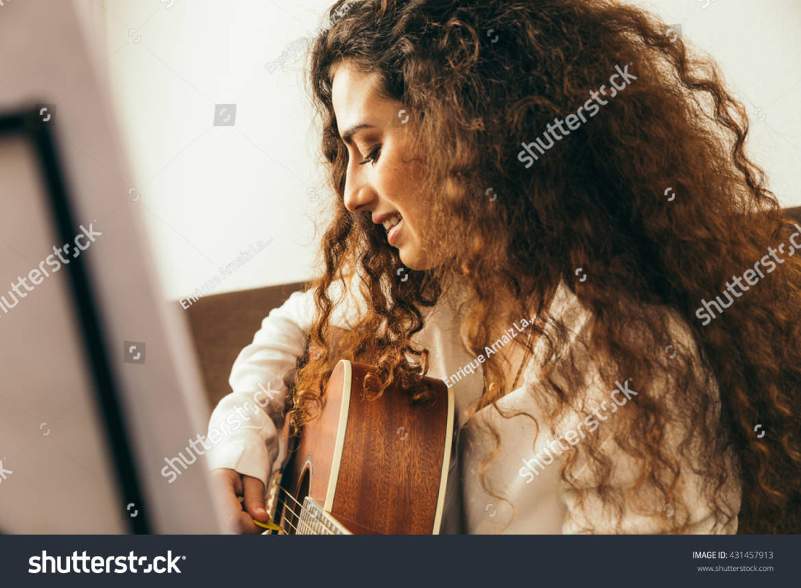 stock-photo-girl-playing-guitar-and-singing-young-woman-with-long-hair-studying-music-at-home-she-plays-431457913.jpg